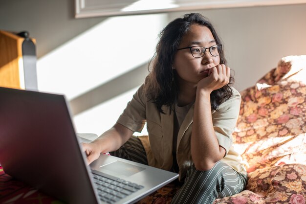 ノートパソコンの前に座っている若い気が散る女性