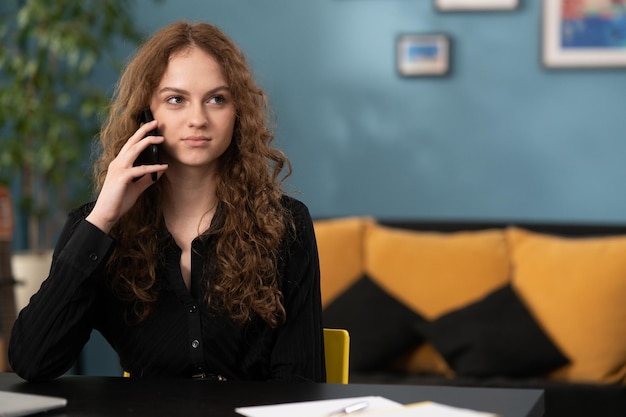 A young disturbed student is talking to a friend on the phone the girl sits on a yellow chair