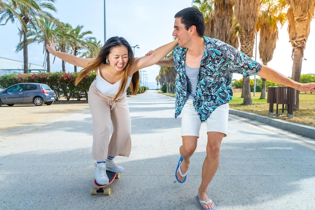 Young diverse couple with skateboard and longboard having fun outdoors