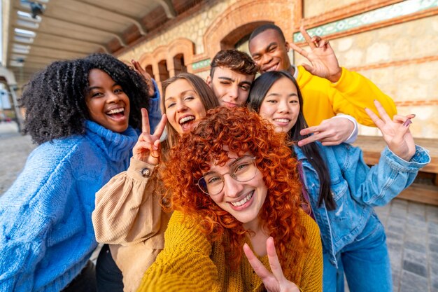 Photo young diverse friends gesturing success while taking a selfie