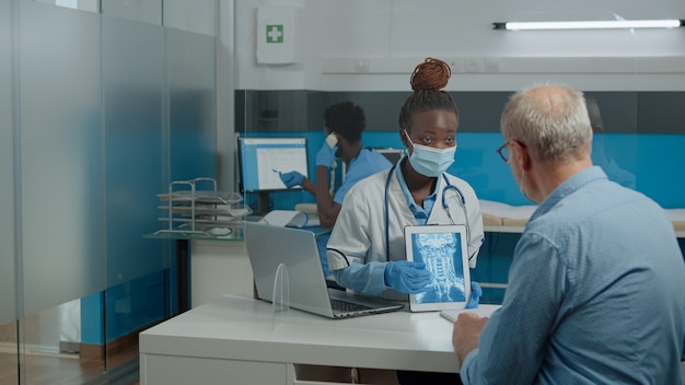 Young doctor analyzing x ray on digital tablet