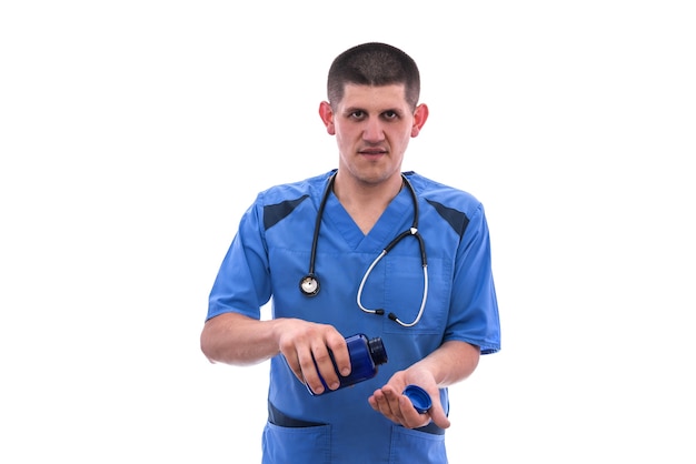 Молодой врач в синей форме принимает таблетки из изолированных банок