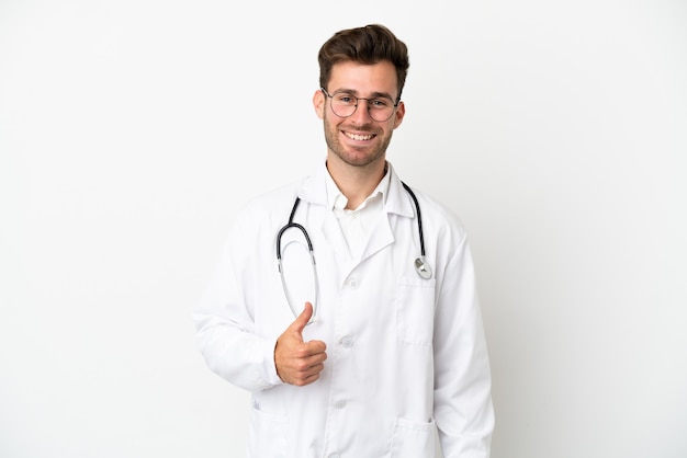 Young doctor caucasian man over isolated on white background wearing a doctor gown and with thumb up