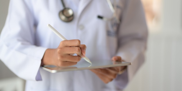 young doctor checking patient chart while using digital tablet