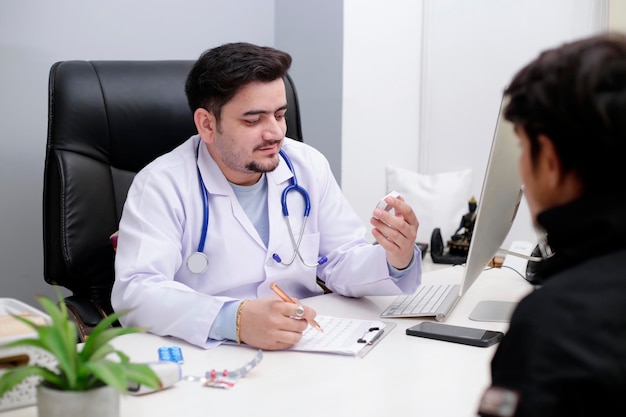 A young doctor is sitting in clinic and giving medicine to patient