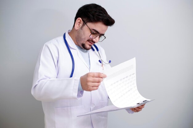 若い医者がレポートチャートを手に持って立って読んでいる