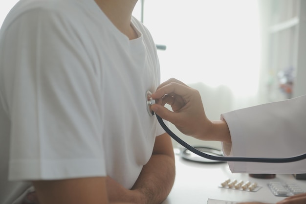 Young doctor is using a stethoscope listen to the heartbeat of the patient Shot of a female doctor giving a male patient a check up