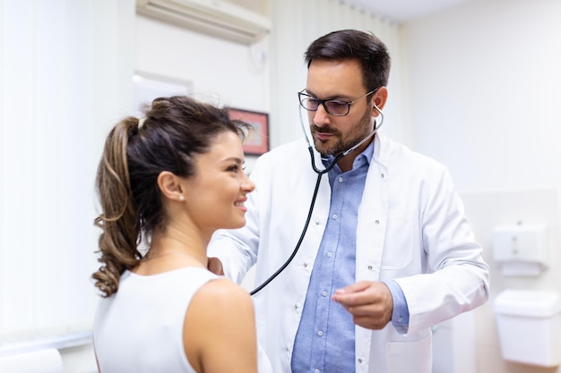 Young doctor is using a stethoscope listen to the heartbeat of the patient Shot of a male doctor giving a female patient a check up