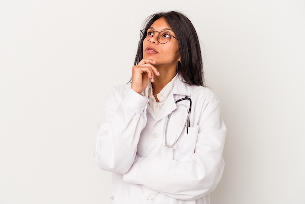 Young doctor latin woman isolated on white background looking sideways with doubtful and skeptical expression.