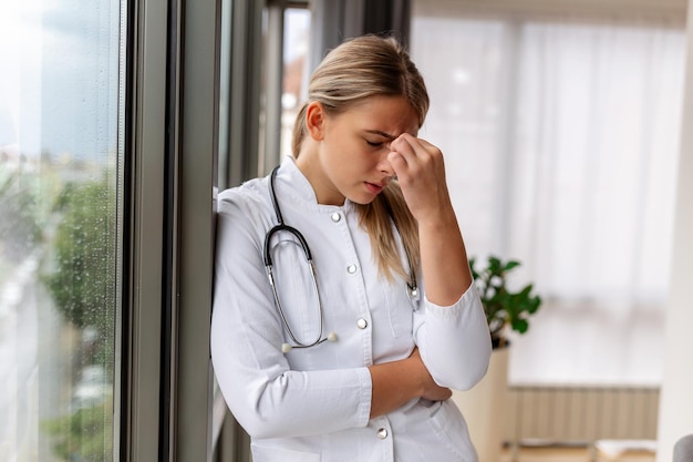 Young doctor looking distressed Tired exhausted female doctor in uniform at hospital holding her head Depressed sad doctor feels burnout stress