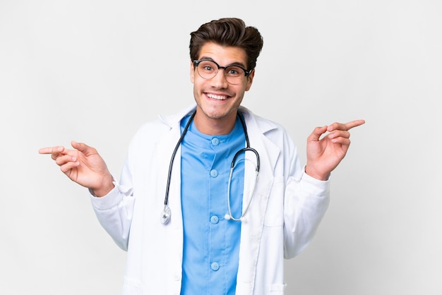 Young doctor man over isolated white background pointing finger to the laterals and happy