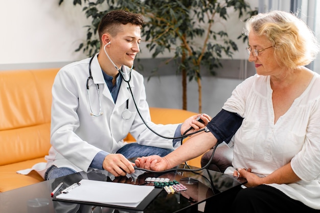 Photo young doctor measuring tension to a patient