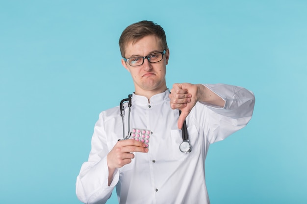 Молодой врач в белом медицинском халате с жестом пальца вниз