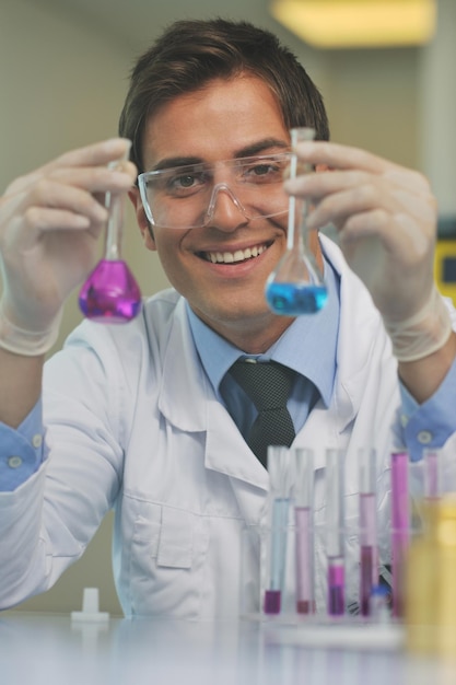 молодой врач-ученый в яркой лабораторной работе исследует и анализирует содержимое пробирок, представляющих химию и исследовательскую концепцию