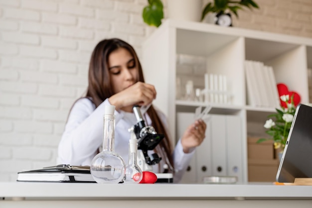 Young doctor or scientist woman using microscope on the background