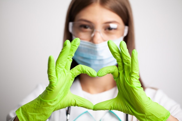 Young doctor shows a heart symbol in gloves