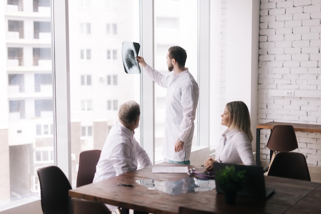 Young doctor stands by the window with an xray