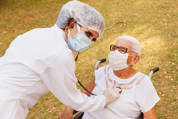 Young doctor taking care of an elderly woman in the park