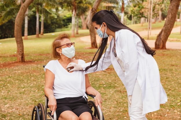 Young doctor taking care of an elderly woman in the park