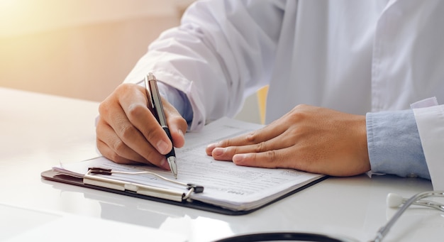 Young doctor who prescribes treatment for patients A young doctor with a formula for writing with a pen to check paperwork. with a stethoscope in the hospital