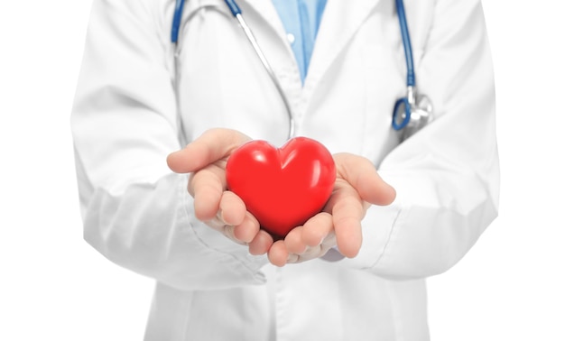 白い背景のクローズ アップ心臓病の概念に小さな赤いハートを持つ若い医者