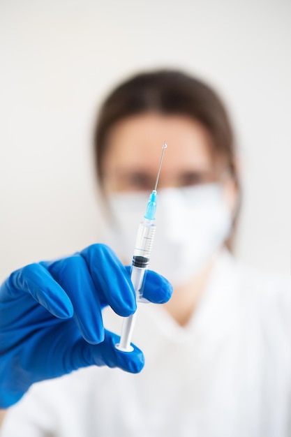 주사기를 손에 든 젊은 의사 실내에서 예방 접종을 하는 의사 진료실에 있는 여성 인플루엔자 및 바이러스 예방 접종