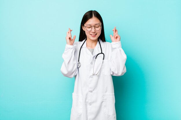 Young doctor woman crossing fingers for having luck