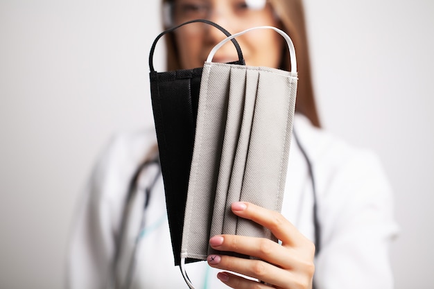 Young doctor woman in glasses holding a protective mask