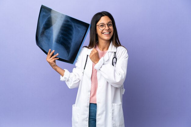 Young doctor woman holding a radiography celebrating a victory