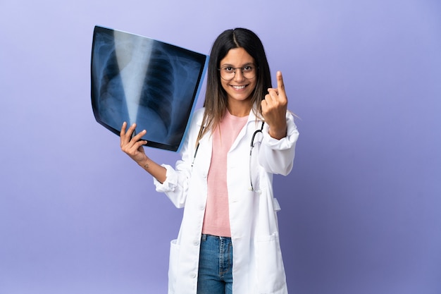 Young doctor woman holding a radiography doing coming gesture