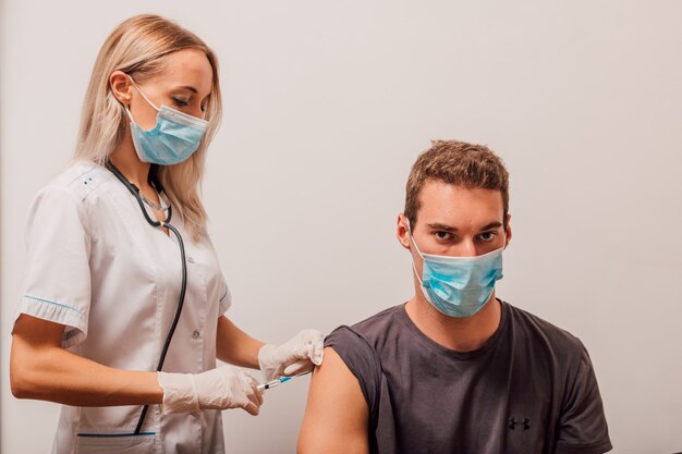 La giovane donna medico fa una vaccinazione per iniezione al paziente nel braccio