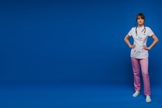 Young doctor woman with stethoscope isolated on blue background.