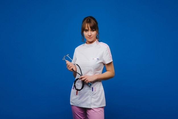 Young doctor woman with stethoscope isolated on blue background.