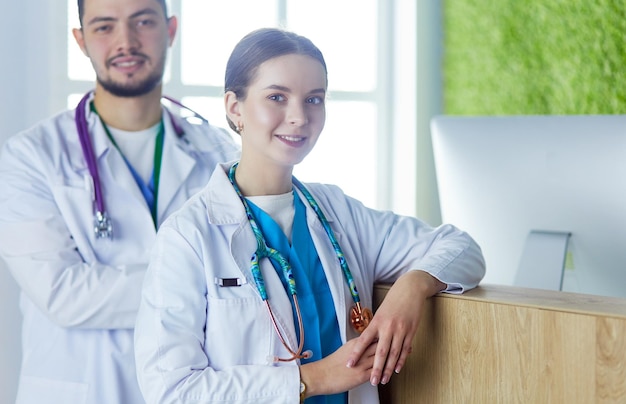 Young doctors are standing inside the hospital and looking at camera