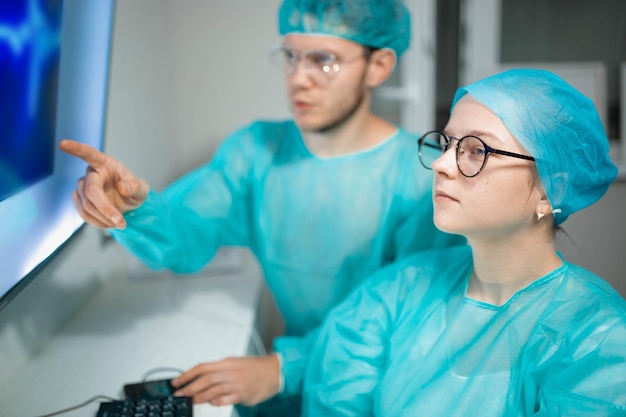 Young doctors colleagues work and study at the computer Male and female surgeons in uniform are stu