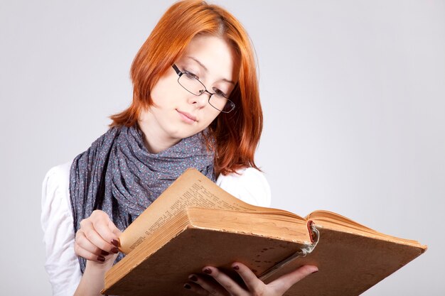 Young doubting fashion girl in glasses with old book