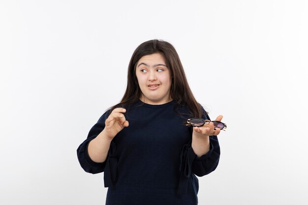 Young down syndrome girl in black sweater holding sunglasses.