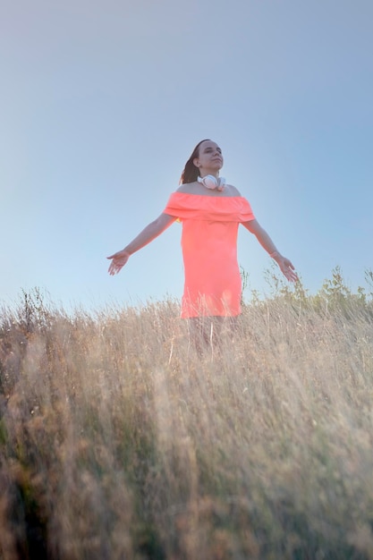 Photo young dreamy woman in dress with closed eyes enjoying strong warm wind in nature