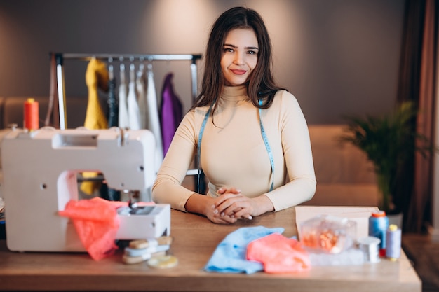 Young dressmaker woman sews clothes on sewing machine