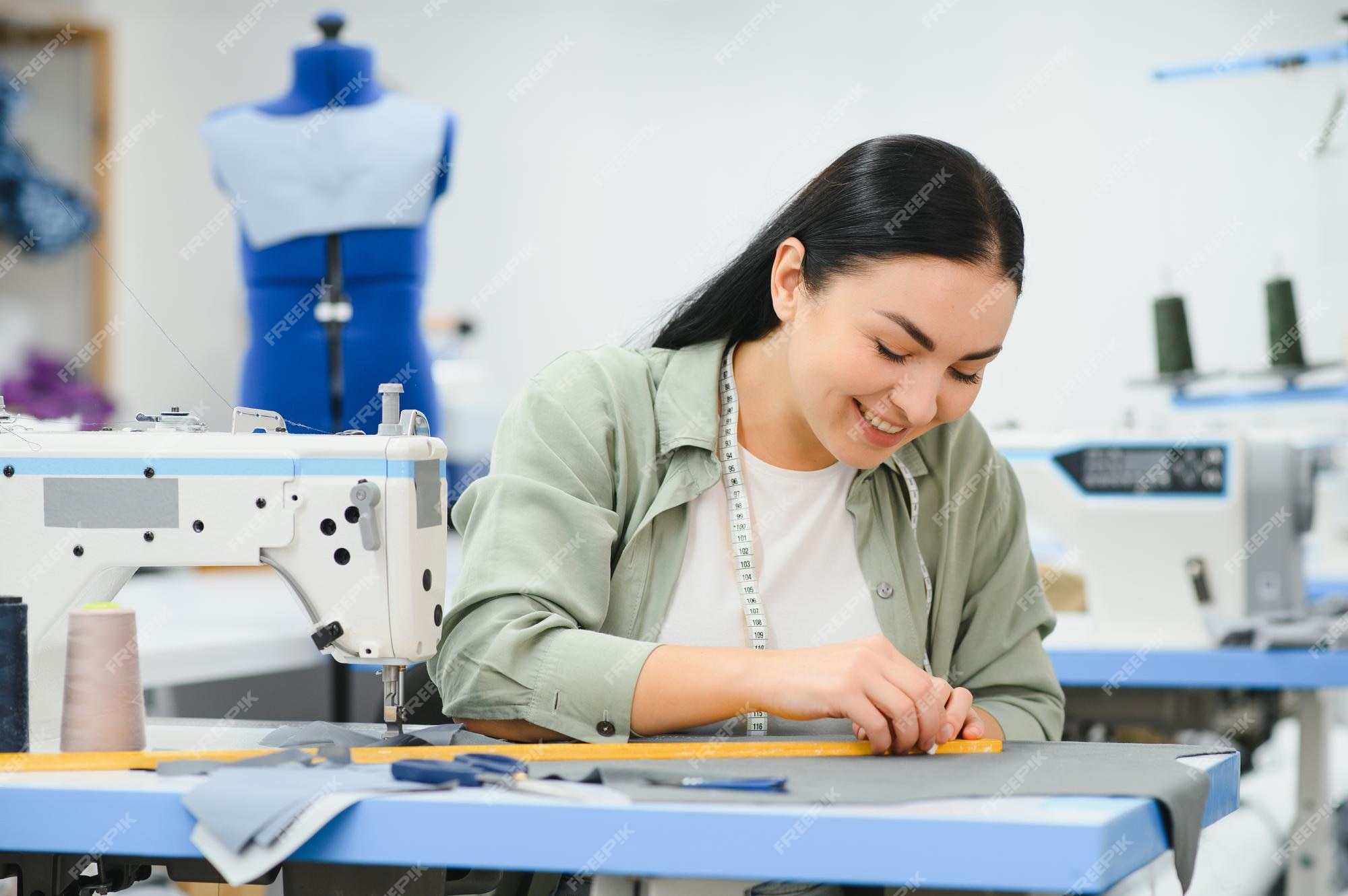 Premium Photo  Young dressmaker woman sews clothes on working table  smiling seamstress and her hand close up in workshop