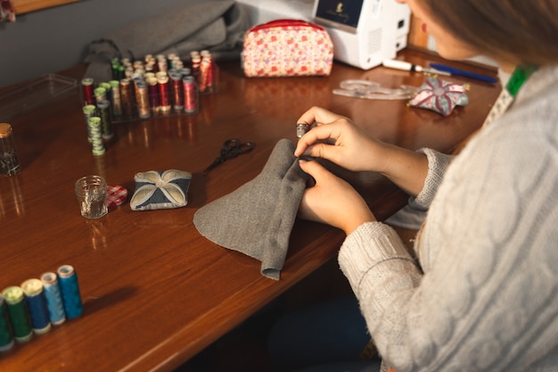 Молодая портниха работает в студии с текстилем