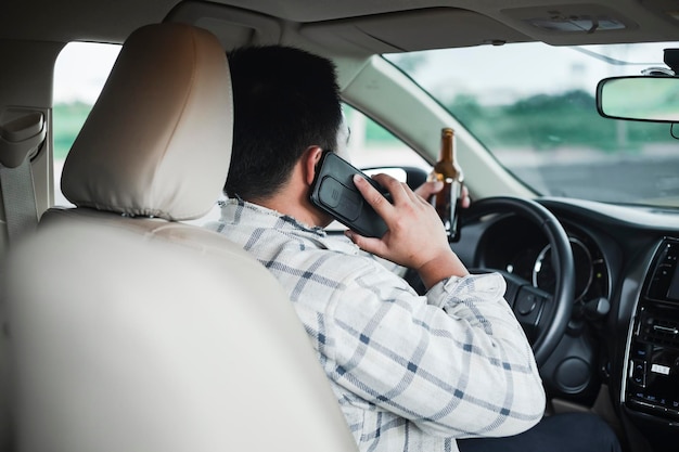 Young Drunk man drinking bottle of beer or alcohol during driving the car dangerously Don't drink and drive concept Don't drink and drive concept Image about careless of accident