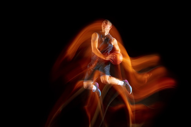 Young east asian basketball player in action and jump in mixed light over dark studio background.
