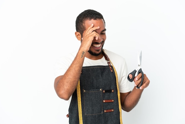 Молодой эквадорский дизайнер держит ножницы на белом фоне и смеется