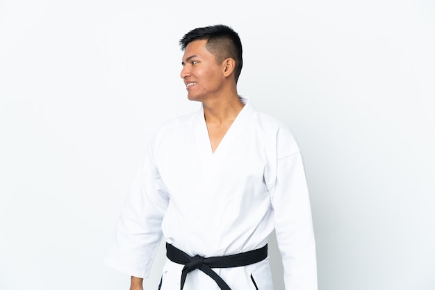 Young Ecuadorian man doing karate isolated on white background looking to the side and smiling