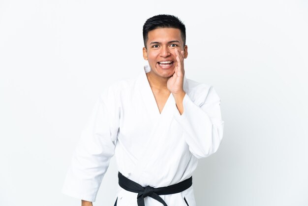 Young Ecuadorian man doing karate isolated on white background shouting with mouth wide open