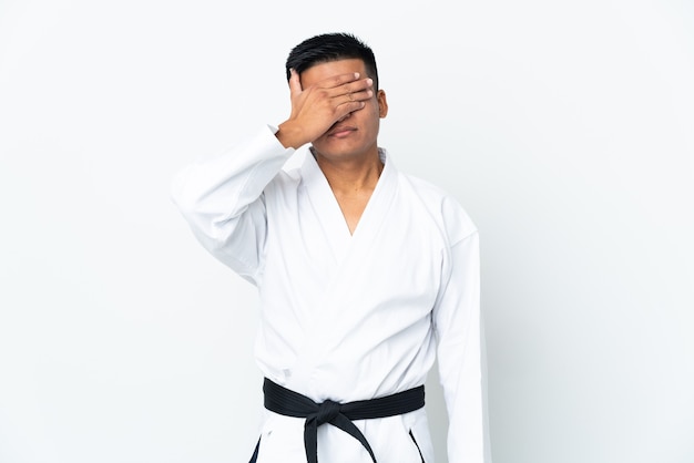 Young Ecuadorian man doing karate isolated on white wall covering eyes by hands. Do not want to see something