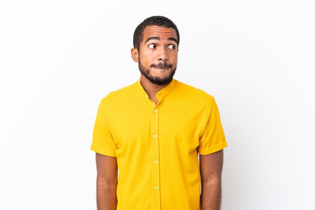 Young Ecuadorian man isolated on white background having doubts while looking up