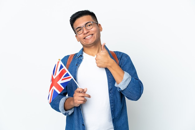 Young Ecuadorian woman holding an United Kingdom flag isolated on white wall giving a thumbs up gesture