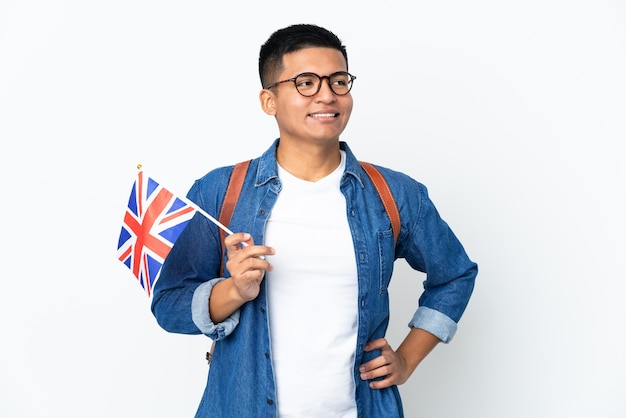 Young Ecuadorian woman holding an United Kingdom flag isolated on white wall posing with arms at hip and smiling